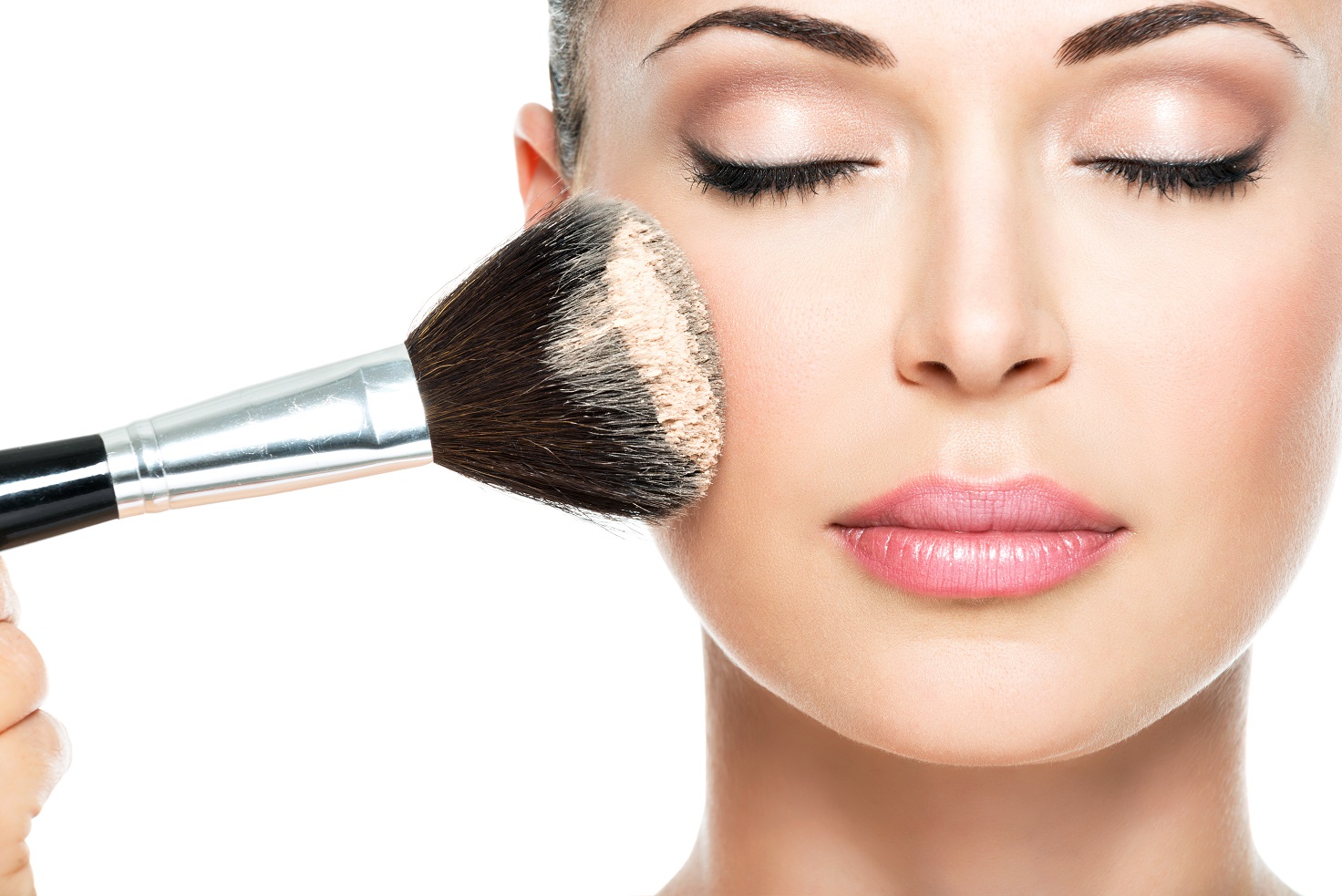 Closeup portrait of a woman  applying dry cosmetic tonal foundation  on the face using makeup brush.